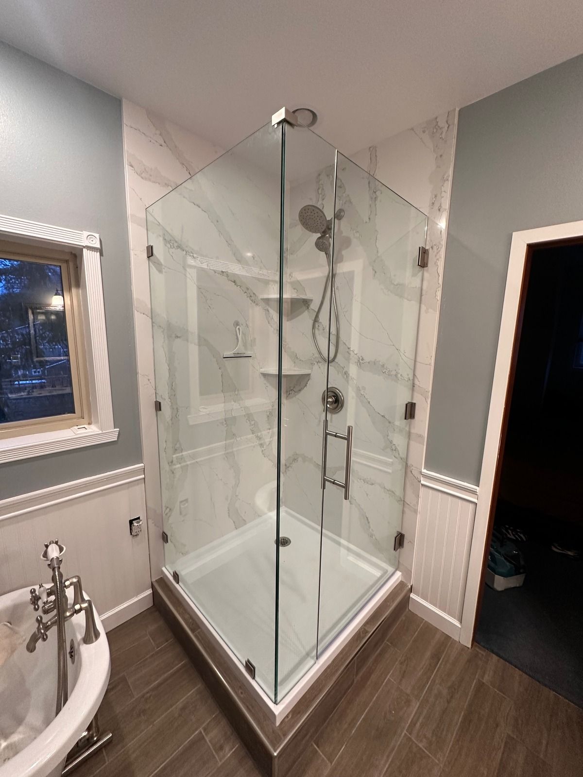 Corner glass shower beside a clawfoot tub