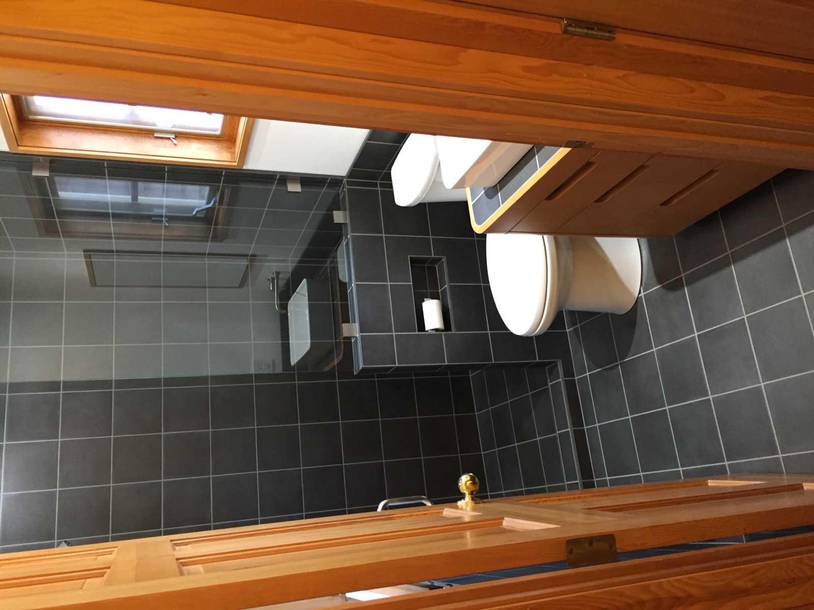 Bathroom remodel with dark tile, glass shower, and wood vanity