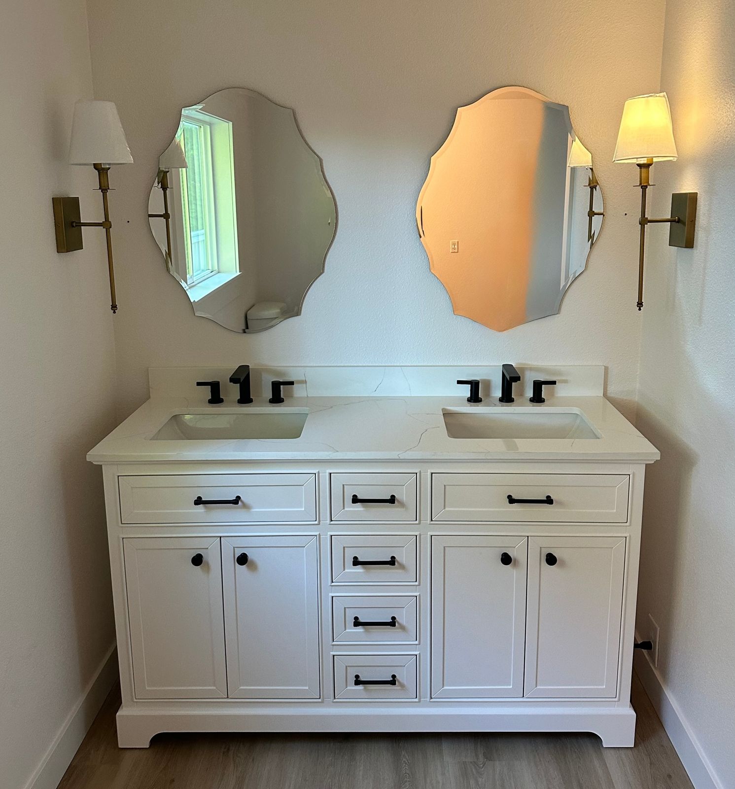 White double vanity with matte-black fixtures and scalloped mirrors