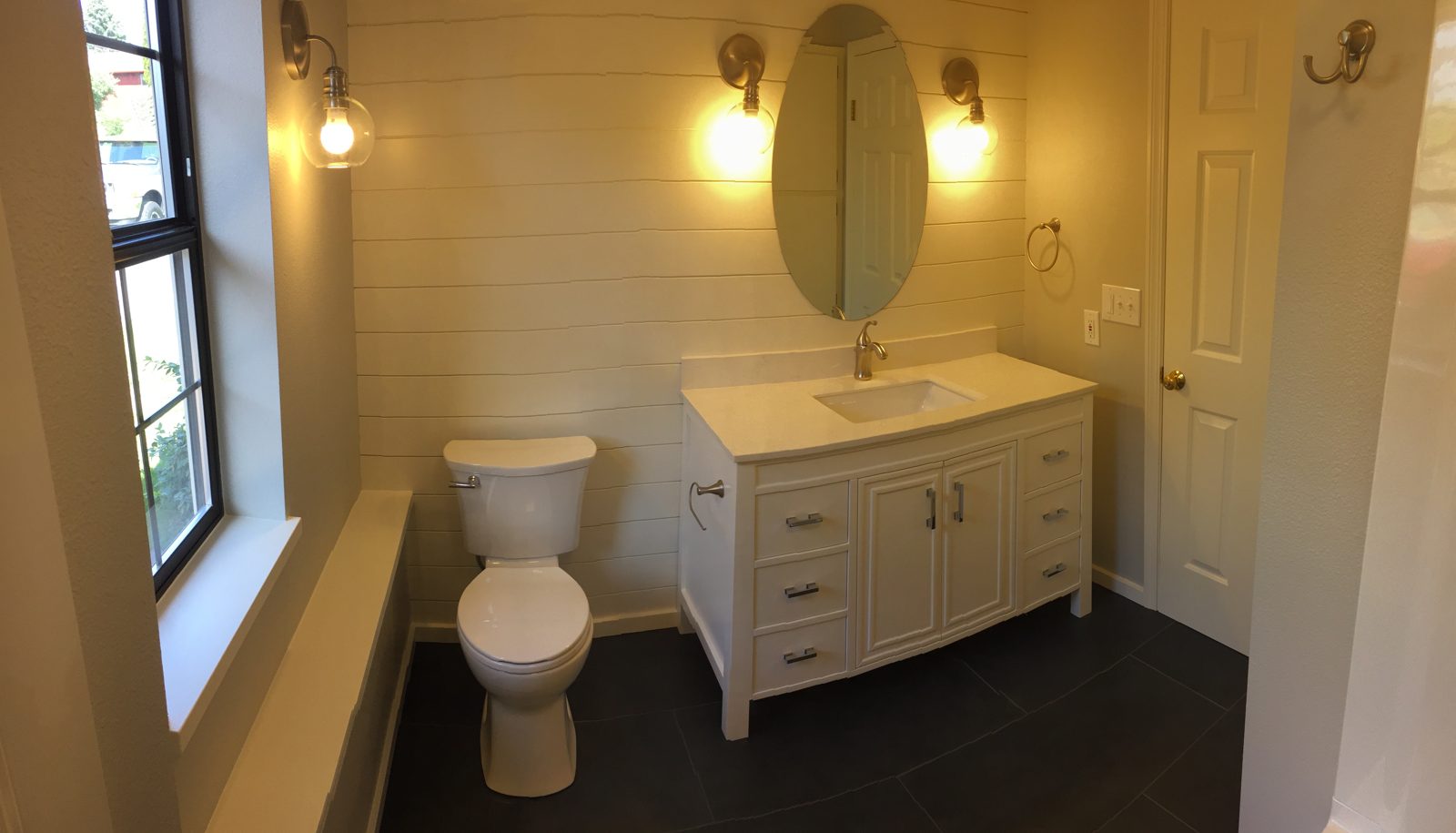 Guest bath with shiplap accent wall, white vanity, and globe sconces