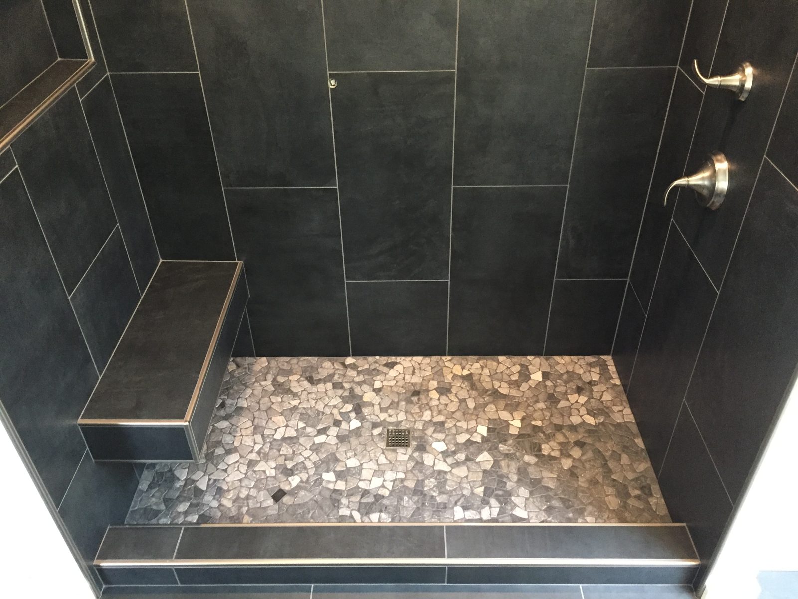 Custom walk-in shower with floating bench and pebble-stone floor
