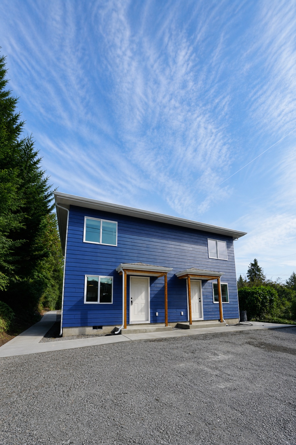 Completed blue two-story detached backyard home with covered entries