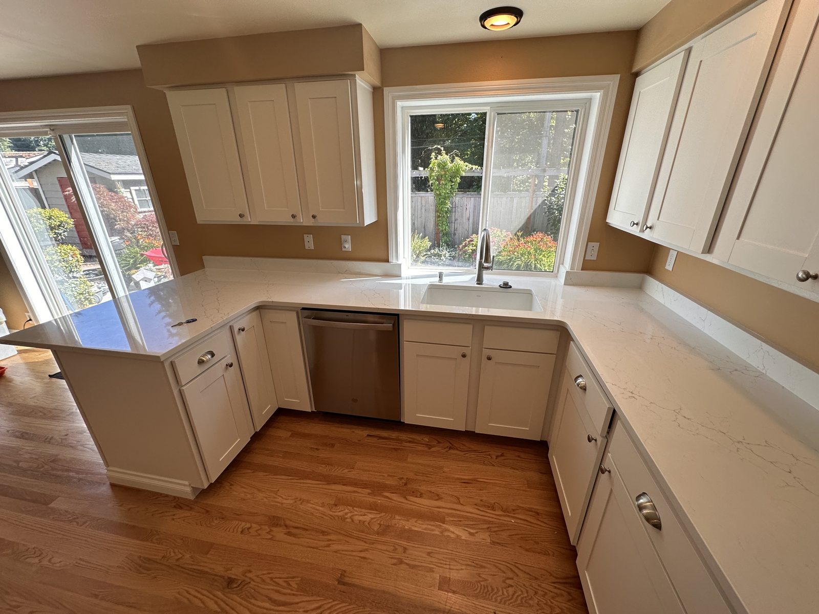 Full kitchen remodel with white shaker cabinets, quartz counters, and refinished hardwood — Edmonds