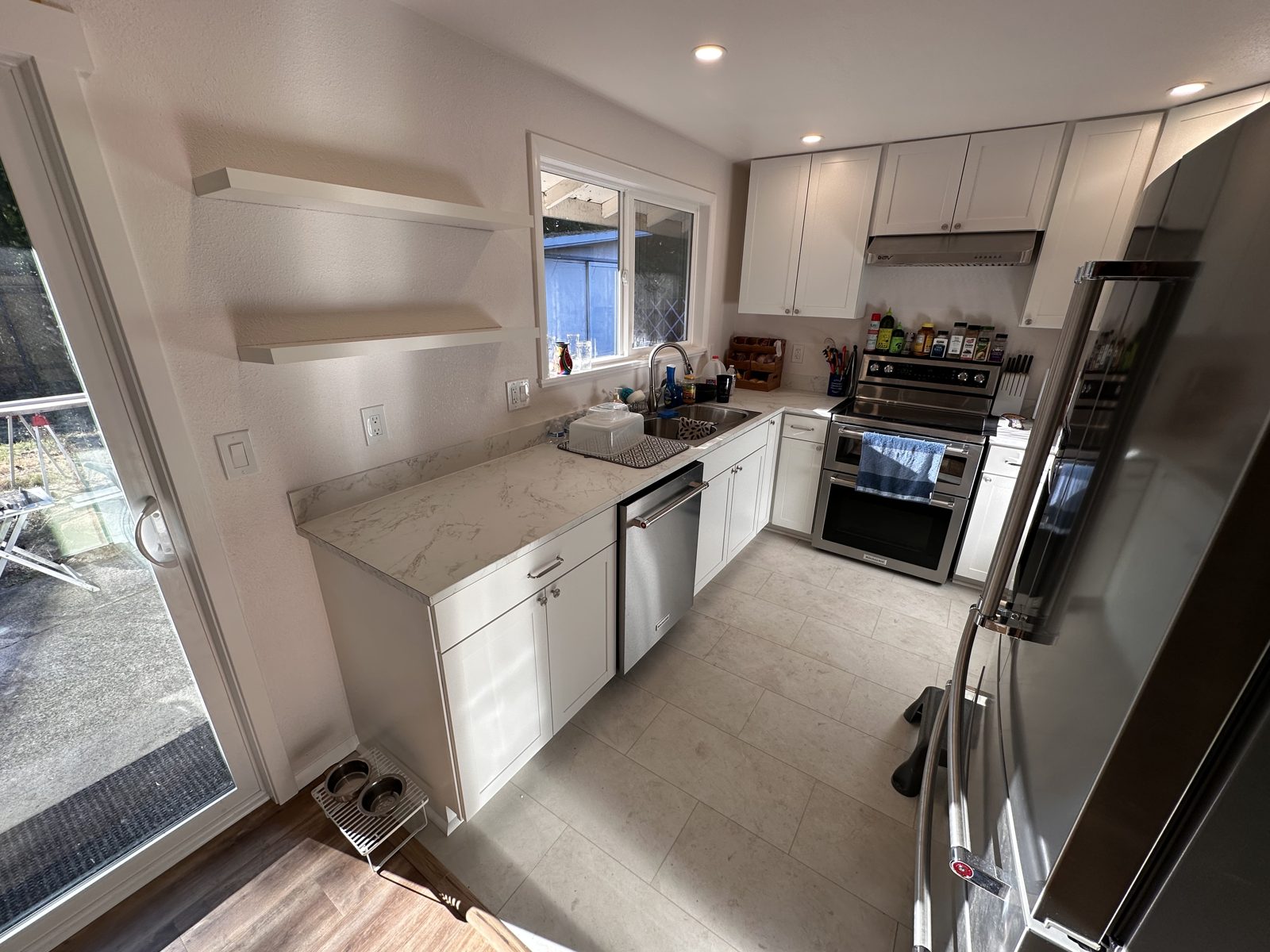 Kitchen remodel with floating shelves, quartz counters, and stainless appliances