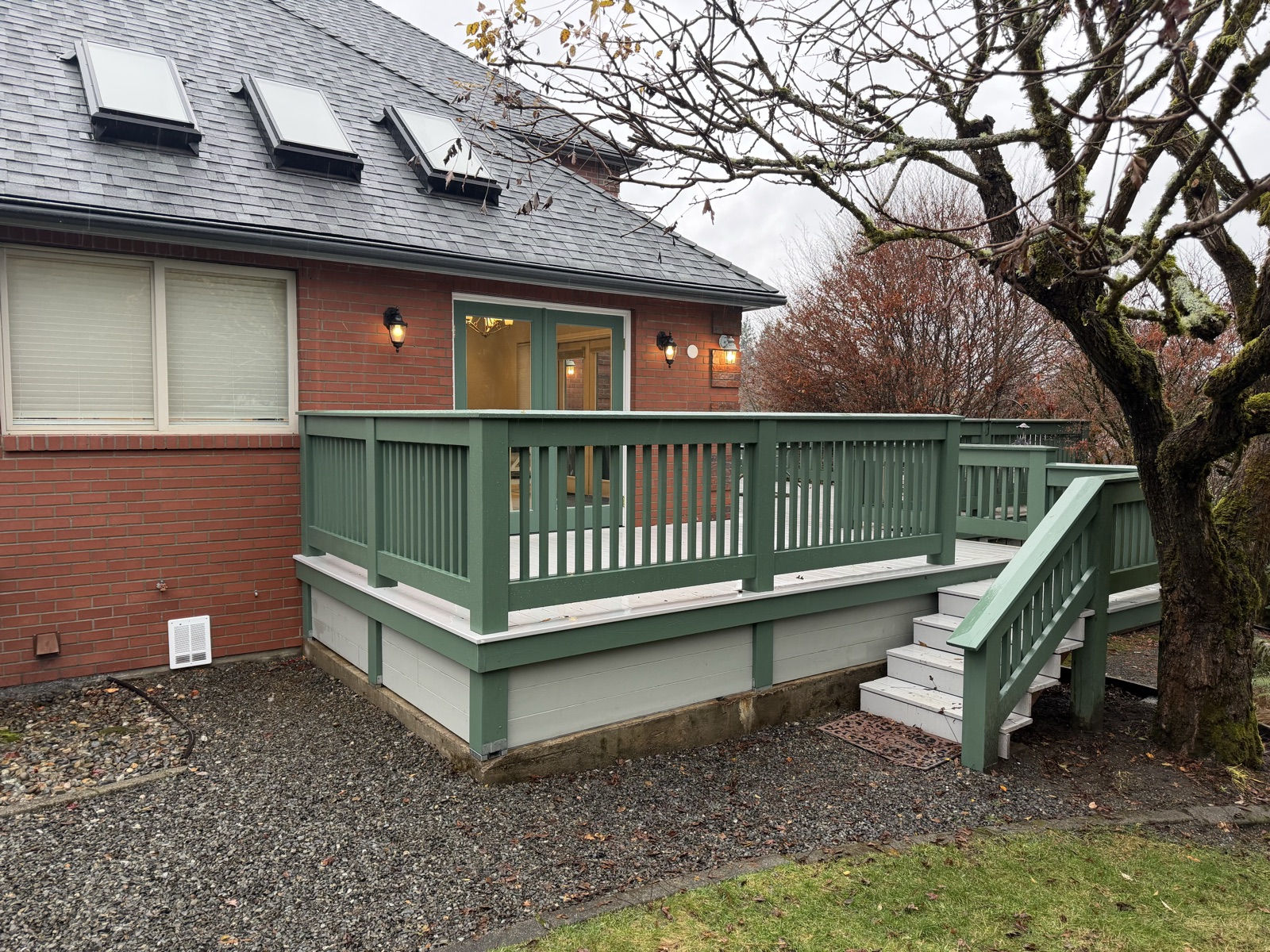 Finished green-railed deck with stairs integrated into the brick home